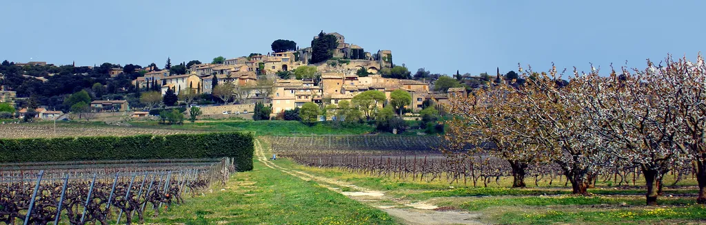 Vue panoramique du village perché de Joucas, ses maisons de pierre dorée et ses ruelles fleuries face aux Monts de Vaucluse, dans le Luberon en Provence