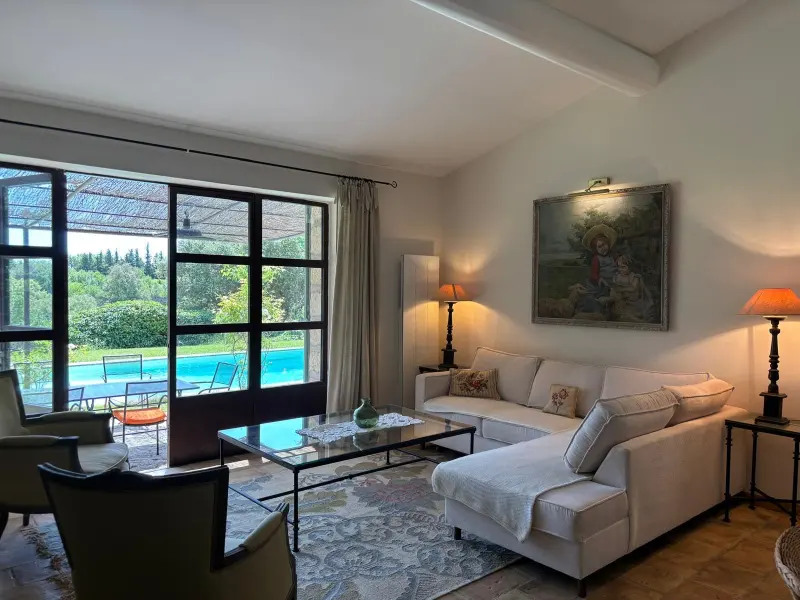 Salon avec canapé d'angle et baie vitrée donnant sur la piscine